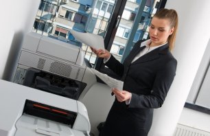 business woman with documents standing next to printer
