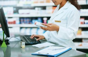 Cropped shot of a pharmacist using a computer while filling a prescription in a chemist
